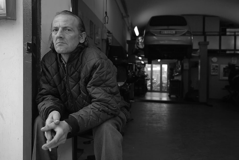 Angelo ha 49 anni e lavora come aiutante in una piccola officina di motocicli e vive in una roulotte. Recupera mobili ed elettrodomestici per strada, li aggiusta e ne arreda la sua “casa”. Ricorda lo sgombero del campo rom avvenuto a poca distanza quasi un anno fa “ … sembrava di essere in guerra, centinaia di poliziotti contro centinaia di nomadi rom; la zona era piena di giornalisti e fotografi. Strano, perché questa zona è sempre dimenticata da tutti…