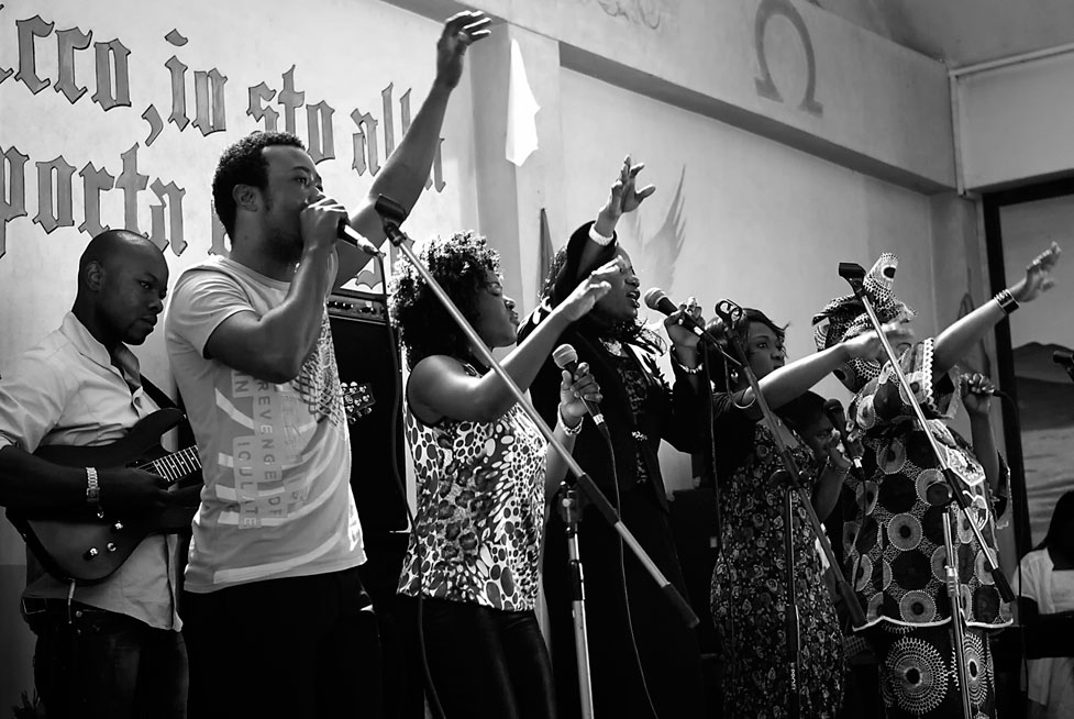 gni domenica Padre Menga tiene il sermone in un piccolo locale della Bovisa per la sua comunità composta da angolani, congolesi e liberiani. Sembra una piccola Africa trapiantata in Bovisa: la messa è accompagnata da canti e balli. L’atmosfera è carica di gioia e di devozione.